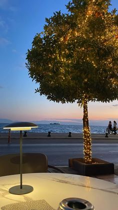 there is a tree that has been decorated with christmas lights at the beach side restaurant