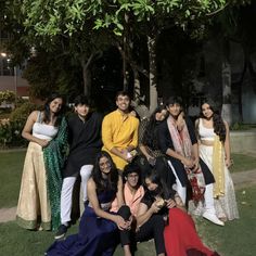 a group of people posing for a photo in front of some trees and grass at night