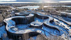 an aerial view of snow covered buildings in the middle of a snowy area with trees and water