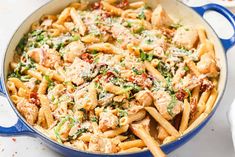 pasta with chicken, spinach and parmesan cheese in a blue skillet