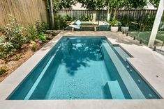 an empty swimming pool in the middle of a backyard with trees and plants around it