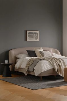 a bed sitting on top of a hard wood floor next to a chair and table