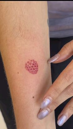 a woman's arm with a small strawberry tattoo on the left side of her arm