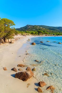 an empty beach with rocks and clear water