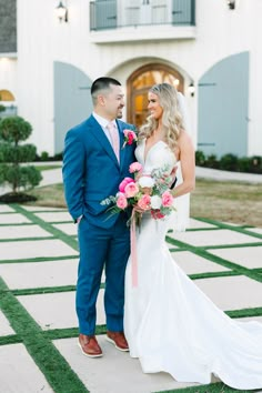 a bride and groom standing in front of a white building with pink flowers on it