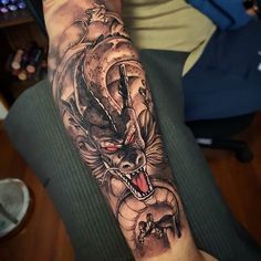 a man's arm with a dragon and snake tattoo on the left side of his arm