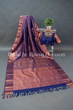 This Dark Purple Copper Zari Kanchi Silk Saree And Blouse is the perfect choice for any festive or wedding occasion. Its elegant flower tassels add a touch of sophistication, while the high-quality silk material provides both comfort and luxury. Make a statement with this stunning saree and blouse set. Flower Tassels, Saree And Blouse, Elegant Flowers, Silk Material, Dark Purple, Silk Saree, Silk Sarees, Tassels, Saree