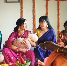 two women are holding a baby while another woman looks at the man in the background