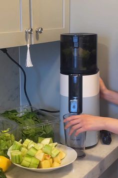 a person is using a juicer to make fresh fruit and vegetables in the kitchen