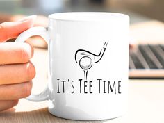 a person holding a coffee mug with the words it's tee time on it