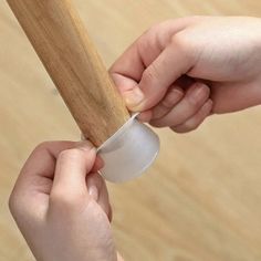 two hands holding an object with a wooden handle and plastic wrap around the top of it