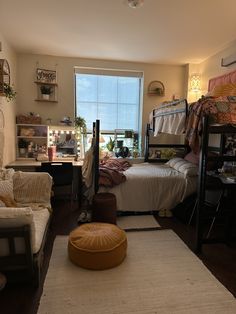 a dorm room with bunk beds, couches and a rug on the floor in front of a window