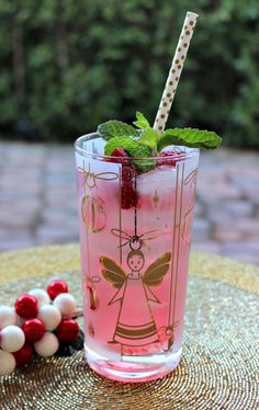 a pink drink sitting on top of a table next to some cherries and strawberries