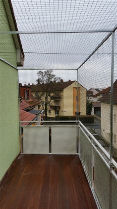 an empty balcony with wooden floors and fenced in area next to the building's roof