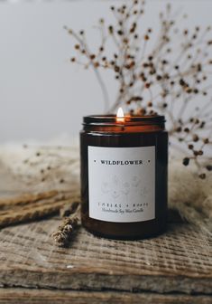 a candle sitting on top of a wooden table next to a plant and some twigs