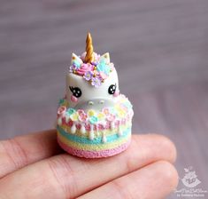 a tiny unicorn cake is sitting on someone's hand