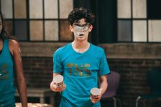 two young people with face paint on their faces and holding cups in front of them