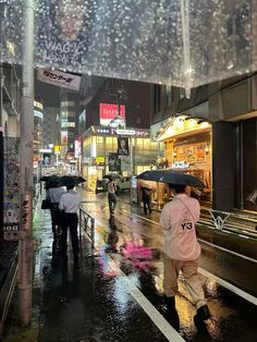 people walking down the street in the rain with umbrellas