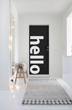 a black door with the word hello on it is in front of a white wall