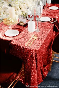 the table is set with red sequined cloths and place settings for four