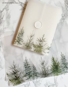 an envelope with trees printed on the front and inside, sitting on top of marbled paper