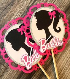 two pink and black fan shaped cake toppers with the word barbie on them