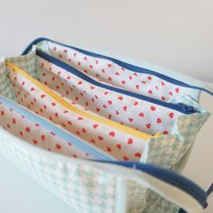 three zippered pouches sitting on top of each other in front of a white wall