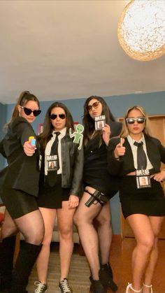 four women in short skirts are posing for the camera with their cell phones and sunglasses on