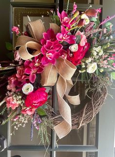 a wreath with pink flowers and greenery on the front door