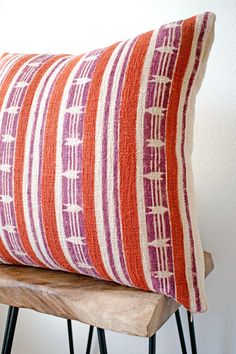 a red and white striped pillow sitting on top of a wooden chair