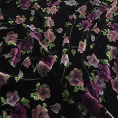 the fabric has flowers on it and is black with pink, purple and green leaves