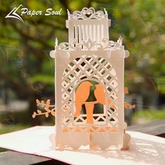 a card with an orange and white paper cut out of the shape of a birdcage