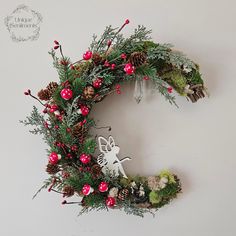 a christmas wreath hanging on the wall with pine cones, berries and other greenery