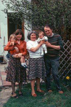 a man, woman and two children standing in front of a house