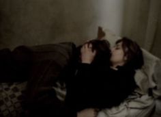 a man and woman laying on a bed with their heads touching each other's noses