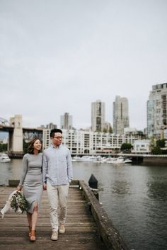 a man and woman walking down a pier next to the water