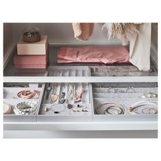 an open drawer filled with jewelry on top of a white shelf next to other items