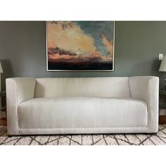 a white couch sitting in front of a painting