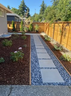 a garden with gravel and rocks in the middle, along side a fenced yard