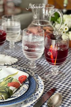 the table is set with glasses, plates and utensils