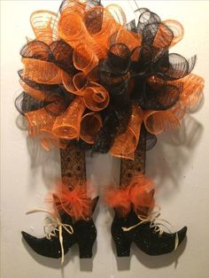 a pair of black and orange boots are hanging on the wall next to a wreath