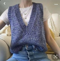 a woman sitting on a couch wearing a sweater vest