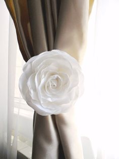 a white rose sitting on top of a curtain