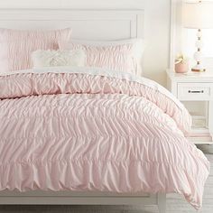 a white bed with pink comforter and pillows