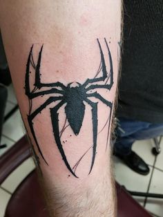 a spiderman tattoo on the leg of a man's arm, with black ink