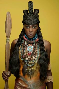 a woman with long black hair holding a stick and wearing an elaborate headdress