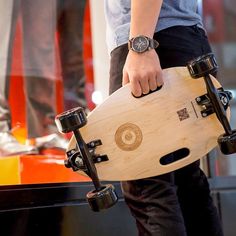 a person holding a wooden skateboard in their hand