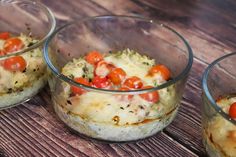 three glass bowls filled with food sitting on top of a wooden table next to each other