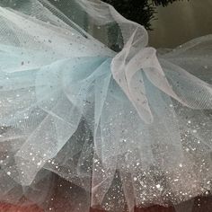 a white tutu skirt hanging from the side of a christmas tree with snow flakes on it