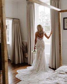 a woman in a wedding dress looking out the window